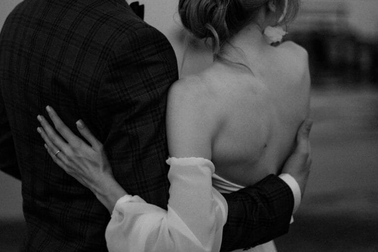 Artystyczne zdjęcie pleców panny młodej i dłoni państwa młodych